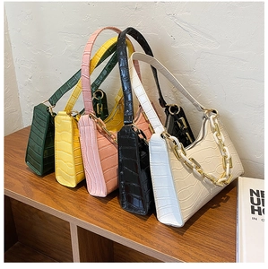 Row of crocodile pattern shoulder bags in various colors with thick chain details