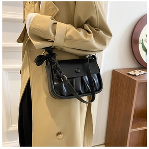 Detail of black pleated cloud bag with elegant satin knot detail on the shoulder strap
