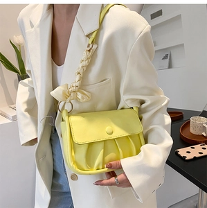 Detail of yellow pleated cloud bag featuring woven shoulder strap and silk bow decoration