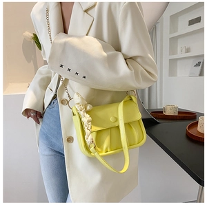 Detail of yellow pleated cloud bag with elegant silk scarf wrap and chain strap