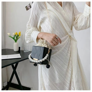 Detail of black leather bucket bag with wave texture and pearl handle accessory