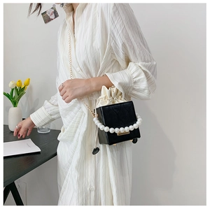 Detail of black box bucket bag with white pearl handle and gold metal chain strap