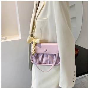 Close-up of lavender ruched cloud bag with gold chain and bow detail on model