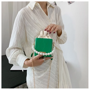 Detail of green embossed mini bucket bag with pearl handle and gold chain strap