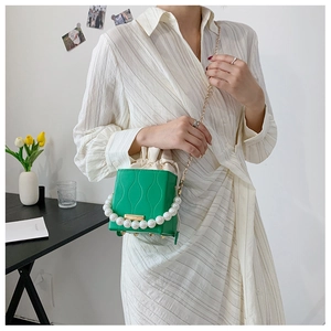 Detail of green bucket bag with pearl handle and textured leather finish