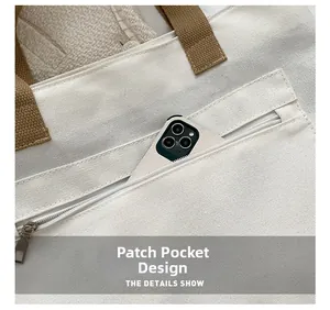 Detail of white canvas tote bag showing the zipper patch pocket and phone storage