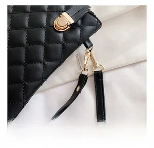 Detail of gold metal buckle and hook on black quilted leather crossbody bag