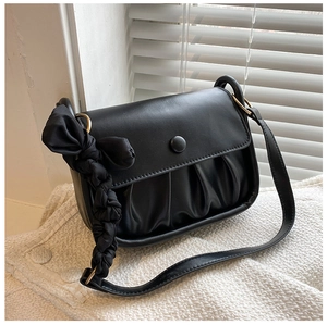 Close-up of ruched black shoulder bag with round clasp and large decorative fabric bow