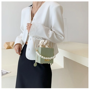 Detail of sage green bucket bag with pearl handle and vertical wavy texture detail