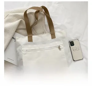 Detail of canvas tote bag showing zippered pocket and blue color block base