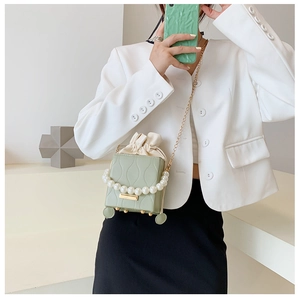 Detail of sage green bucket bag with pearl handle and wavy embossed texture on leather