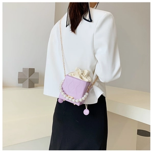 Detail of purple wavy textured bucket bag with pearl handle and golden chain strap
