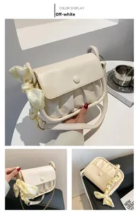 Detail of cream pleated cloud bag with a silky bow strap and magnetic snap closure