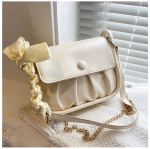 Close-up of cream pleated shoulder bag with silk-wrapped handle and gold chain strap