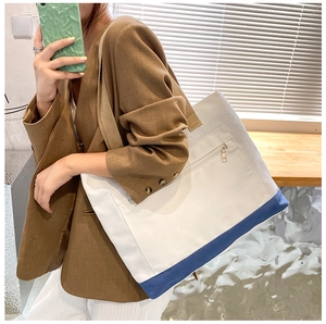 Detail of canvas tote bag showing two-tone contrast and front zipper pocket texture