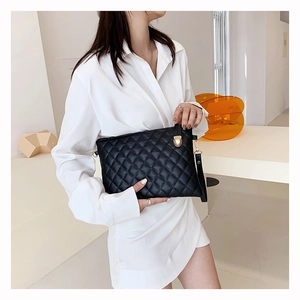 Detail of black quilted leather envelope clutch with golden turn-lock and wrist strap