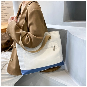 Detail of canvas tote bag showing the front zipper pocket and blue contrast bottom