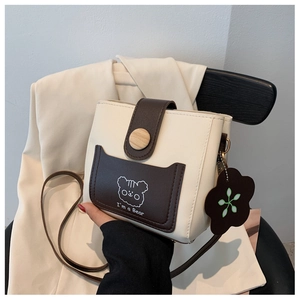 Detail of printed bucket bag with flower charm and wooden button on faux leather flap