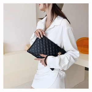 Detail of black quilted shoulder bag featuring golden metal lock and wrist strap