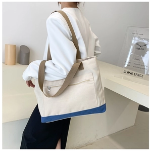 Detail view of a canvas tote bag featuring navy blue base and brown woven handles