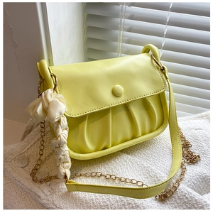 Close-up of yellow pleated cloud bag with metal chain strap and silk scarf detail
