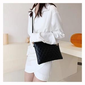 Side view of black quilted faux leather crossbody bag worn with a white shirt