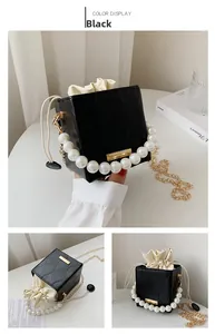 Detail of black quilted bucket bag with pearl handle, gold chain and drawstring closure