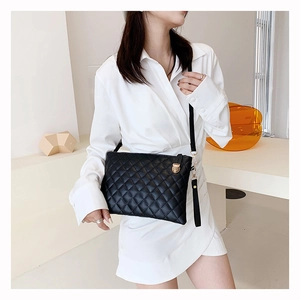 Detail of black quilted leather shoulder bag with gold clasp and elegant chain strap