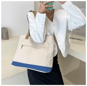 Canvas tote bag with blue striped bottom showing side view of shoulder strap on model