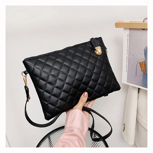 Detail of black quilted PU leather crossbody bag featuring a golden metal twist lock