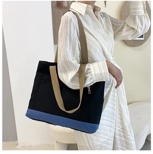 Detail of color-block canvas tote bag with wide khaki shoulder strap and black body