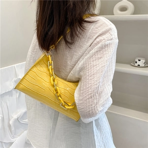 Yellow faux crocodile underarm bag with thick resin chain strap on a white background