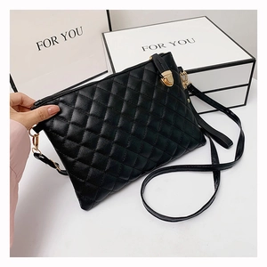Detail of black quilted PU leather crossbody bag with gold hardware and gift packaging