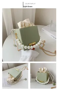 Detail of light green bucket bag with pearl handle, drawstring liner, and chain strap