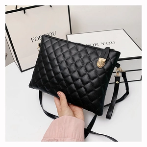Detail of black quilted PU leather crossbody bag featuring a golden metal twist lock