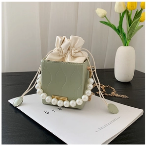 Close-up of sage green bucket bag with pearl handle and wave pattern texture