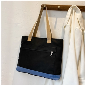Close-up of color-block canvas tote bag with front zipper pocket and khahi handles