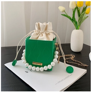 Detail of green bucket bag with wave texture, pearl handle and golden chain strap