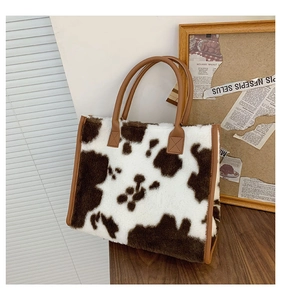 Dettaglio borsa tote in ecopelliccia muccata con manici in pelle marrone su tavolo