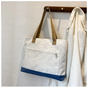 Close-up of canvas tote bag featuring blue contrast base and functional front zipper pocket