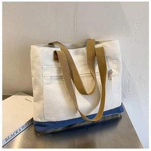 Detail of off-white canvas tote bag with blue trim and front zipper pocket detail