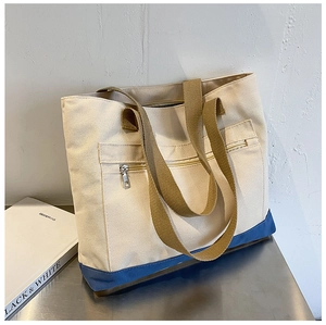 Detail of canvas tote bag with deep blue contrast bottom and silver front zipper pocket