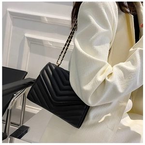 Détail du sac bandoulière noir matelassé avec surpiqûres en V et chaîne en métal