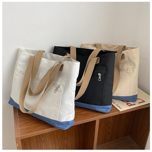 Detailed view of large canvas tote bags in white and black with blue base on wood stand