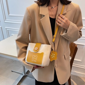 Chic beige and yellow bucket bag with bear print and flower charm shown on model