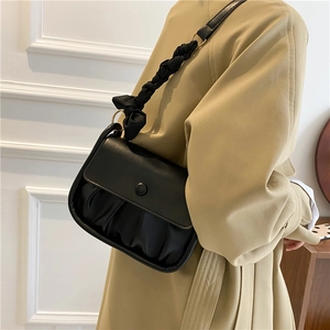Minimalist black pleated cloud bag with a unique woven strap and bow detail on the side
