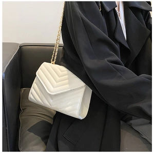 Détail d'un sac blanc matelassé en V avec bandoulière en chaîne dorée élégante