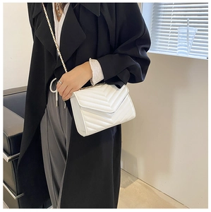 Gros plan du sac bandoulière blanc matelassé en V avec bandoulière en chaîne dorée