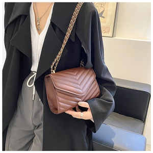 Sac bandoulière marron en similicuir matelassé en V avec bandoulière chaîne sur un mannequin