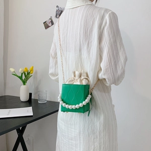 Green textured crossbody bucket bag with pearl handle and gold chain strap